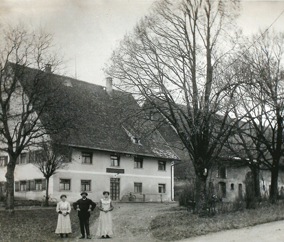 Schwarzweiß-Foto eines traditionellen Gasthauses mit Bäumen davor