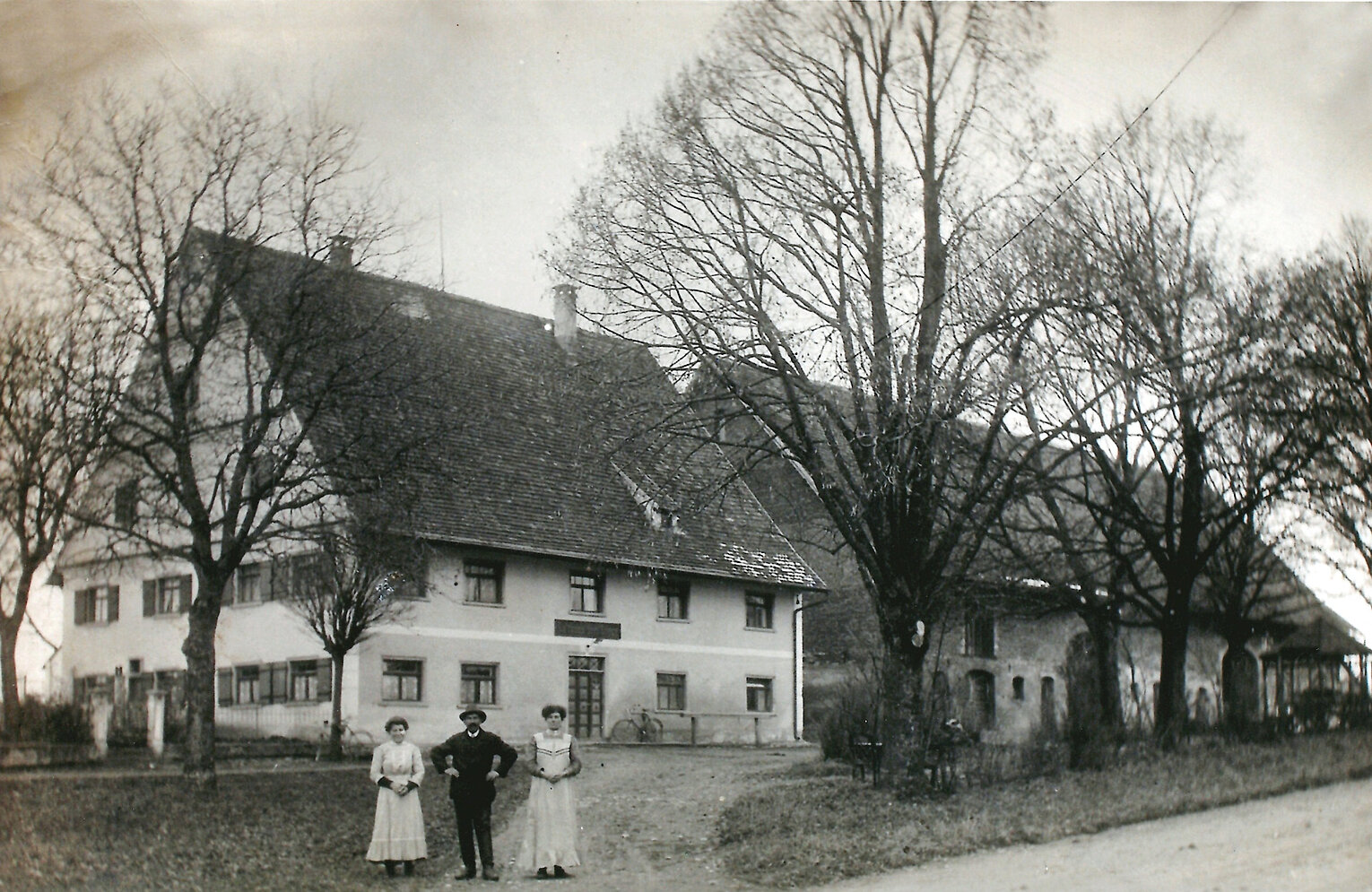 Schwarzweiß-Foto eines traditionellen Gasthauses mit Bäumen davor