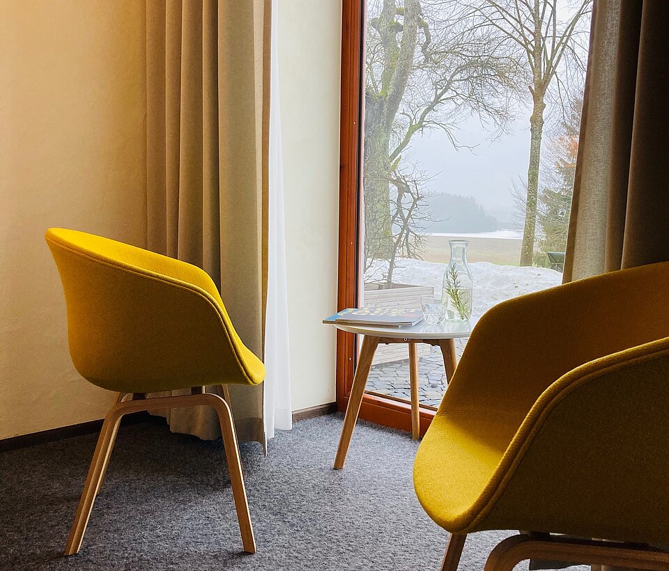 Sitzecke mit gelben Stühlen in einem Hotelzimmer