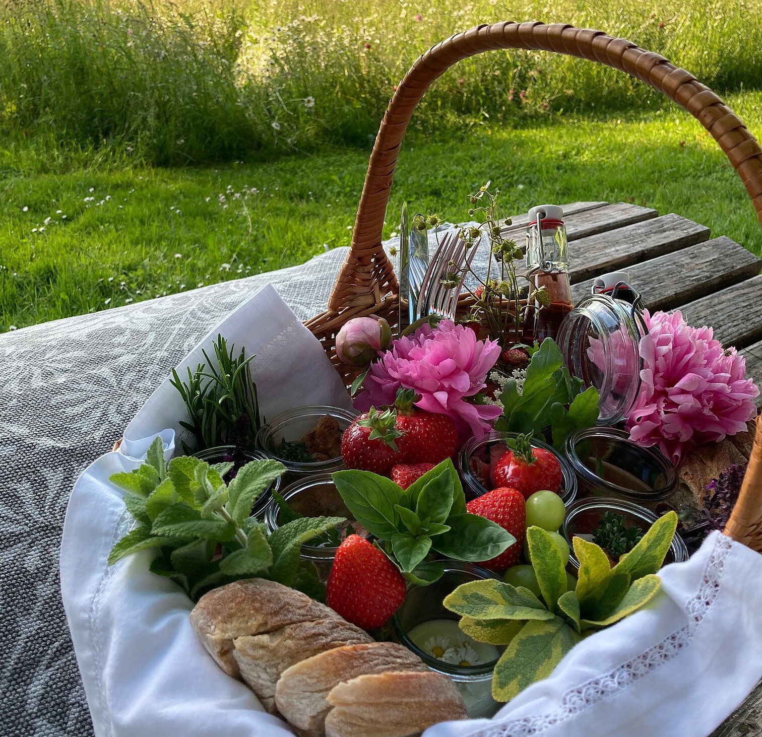 Picknickkorb steht auf einem Holztisch im Grünen