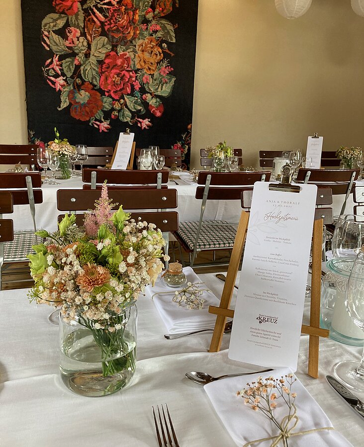 Heller Gastraum mit eingedeckten Tischen und Blumenschmuck