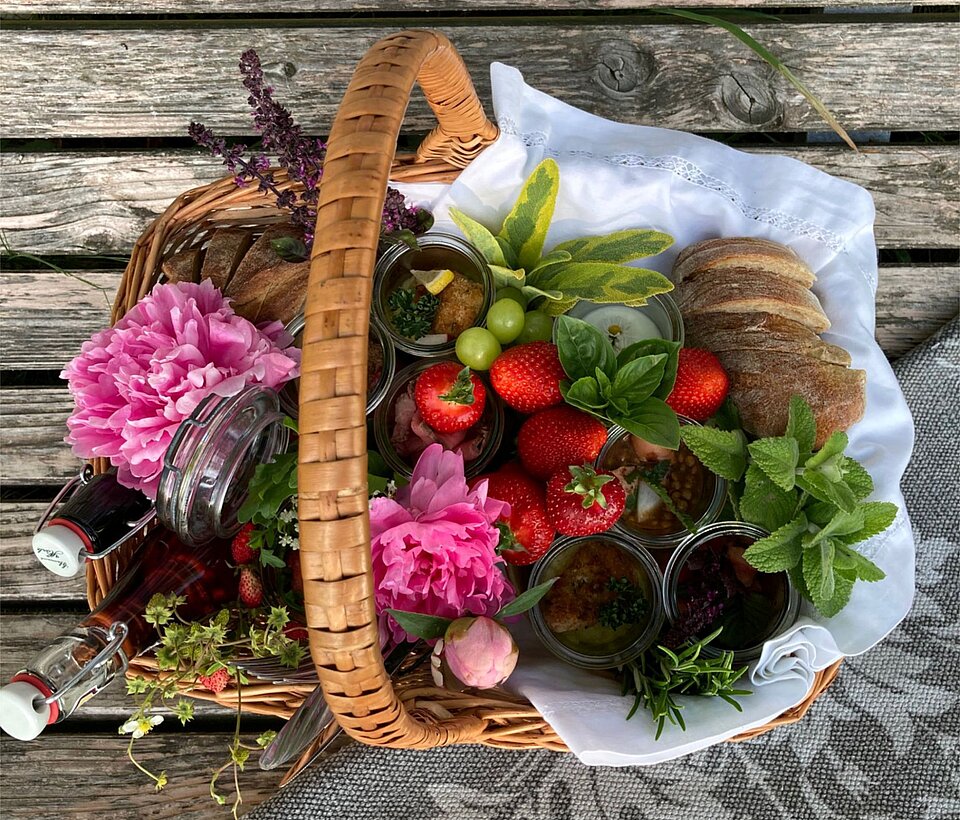 Bunter Korb mit Blumen und Gemüse auf Holzboden