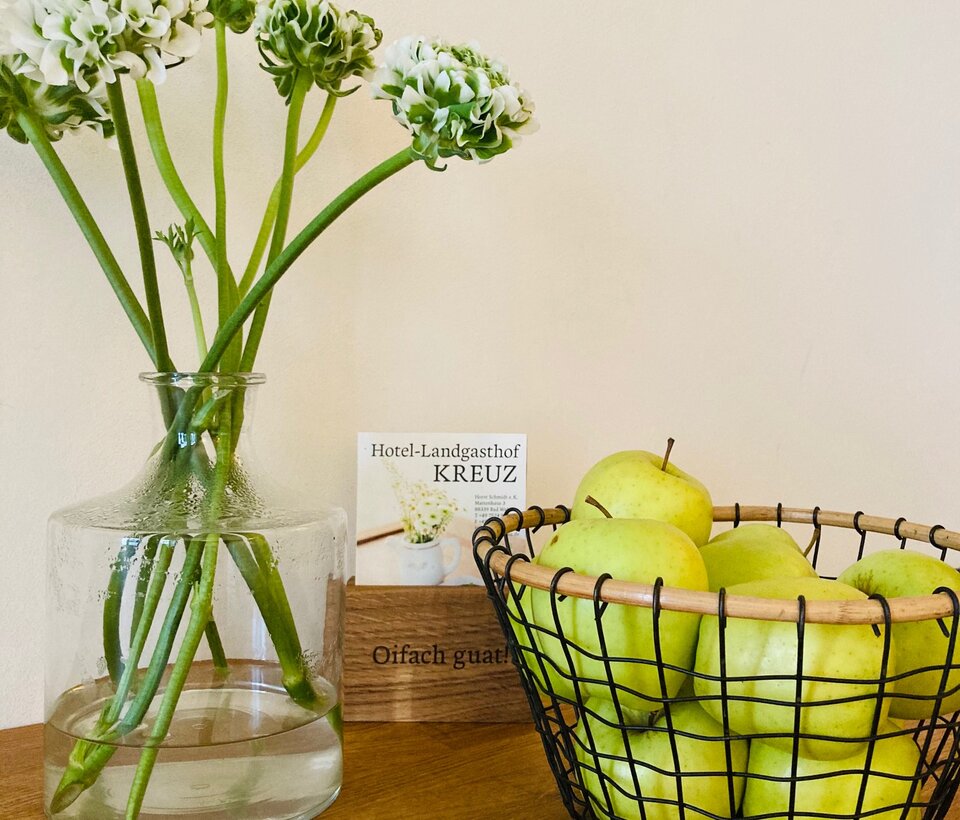 Vase mit weißen Blüten und grüne Deko auf Holztisch im Hotel-Landgasthof KREUZ